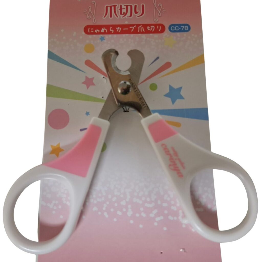 にゃめらカーブ爪切りのパッケージ上に爪切りを開いた状態で置いている。