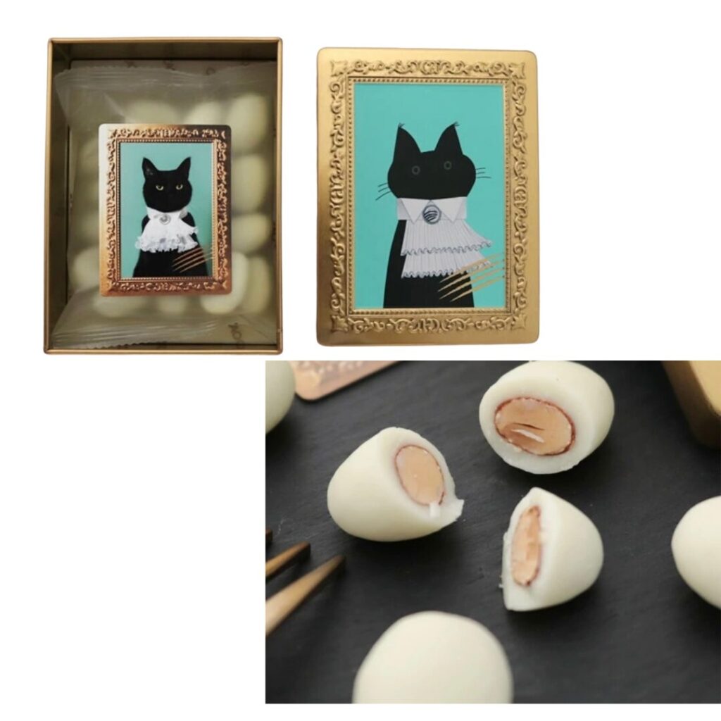 金色の豪華な額縁に描かれた黒猫のイラストが特徴的なチョコレート缶と、その中身であるホワイトチョコレートでコーティングされたアーモンド菓子の断面画像。